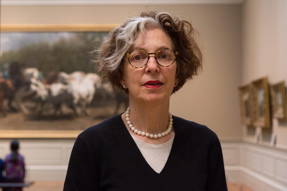 woman standing in front of paintings in museum gallery