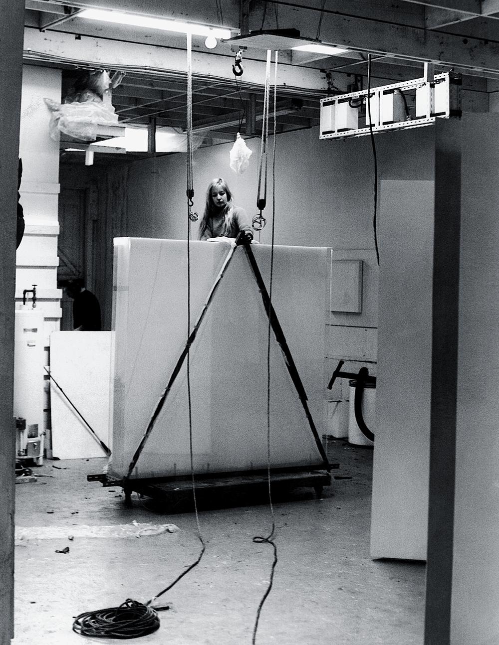 Mary standing over a large canvas on a rolling transport cart