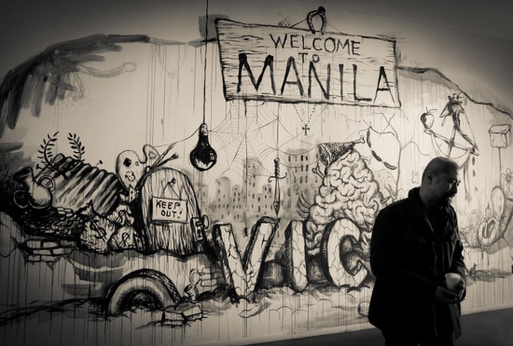 artist in front of exhibition title wall