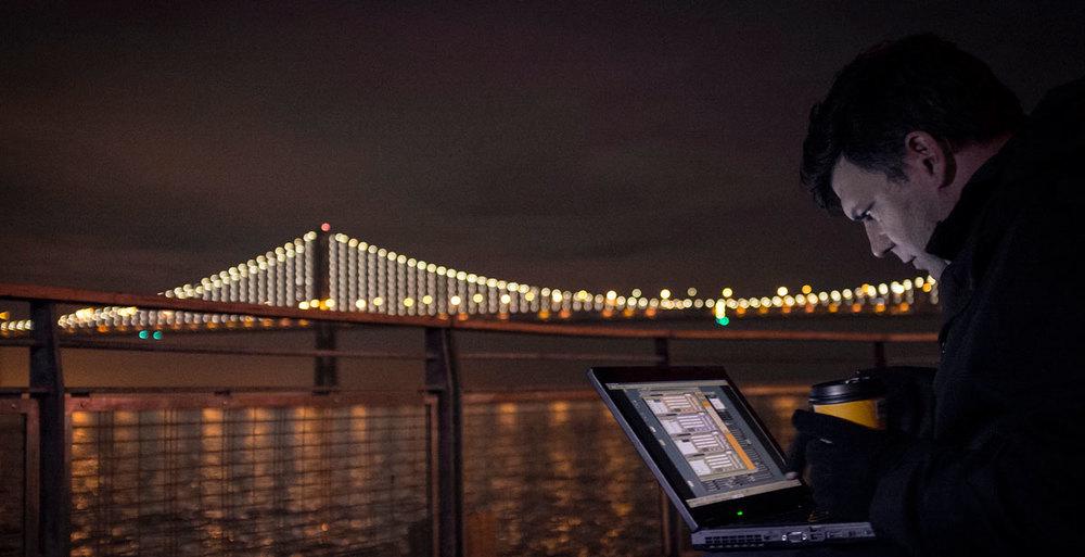 Leo to the left with bridge illuminated at night in the background